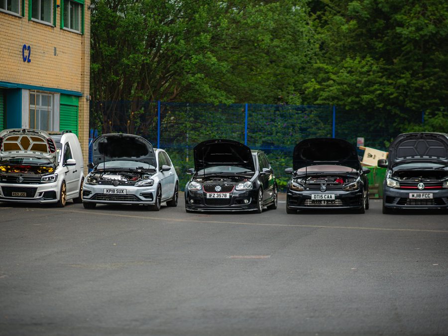 Five Volkswagens lined up outside a workshop unit with bonnets open, all fitted with Audi RS3 2.5 TFSI engine conversions